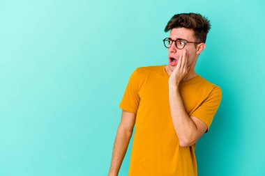 Kafkasyalı genç adam mavi arka planda izole edilmişti. Gördüğü bir şey yüzünden şok olmuştu..