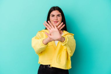Mavi arka planda izole edilmiş genç beyaz bir kadın inkar jesti yapıyor.