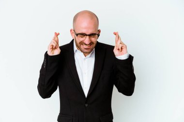 Genç beyaz tenli kel adam, şans dilemek için mavi arka planda izole edildi.