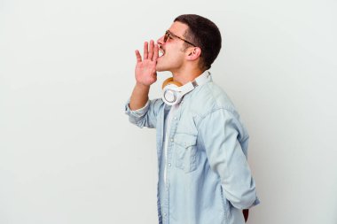 Beyaz arka planda izole edilmiş müzik dinleyen beyaz tenli genç bir öğrenci bağırıyor ve avuç içi kadar açık bir ağız tutuyor..