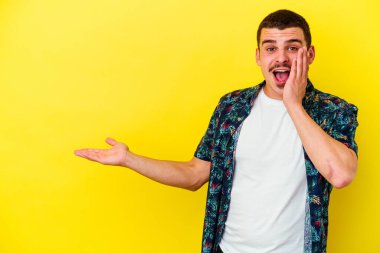 Sarı arka planda izole edilmiş beyaz bir adam, avuç içinin fotokopi alanını tutmaktan etkilenmiş..