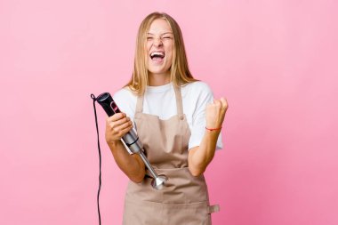 Genç Rus aşçı kadın elinde elektrikli mikser tutuyordu. Tezahürat yapıyordu ve heyecanlıydı. Zafer konsepti.