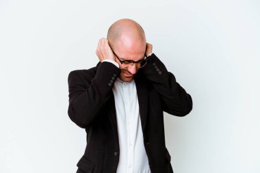 Genç, beyaz, kel bir adam mavi arka planda izole edilmiş kulakları elleriyle kapatıyor..