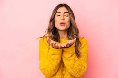 Beyaz tenli genç bir kadın, dudaklarını katlayıp, avuç içi tutarak hava öpücüğü yolluyor..