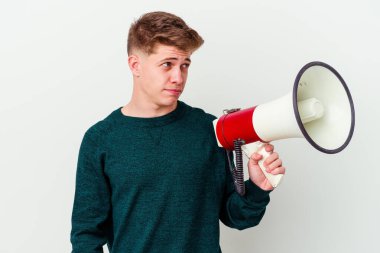 Beyaz arka planda izole edilmiş bir megafon tutan genç beyaz bir adam kafası karışmış, kuşkulu ve güvensiz hissediyor..