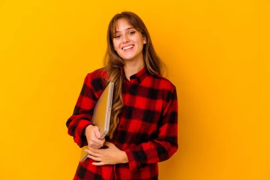 Dizüstü bilgisayar tutan genç beyaz kadın mutlu, güler yüzlü ve neşeli..