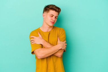 Kafkasyalı genç adam mavi arka planda izole edilmiş, güler yüzlü ve mutlu..