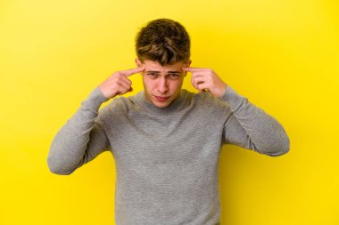 Sarı arka planda izole edilmiş genç beyaz adam bir göreve odaklanmış, işaret parmaklarını işaret ediyor..