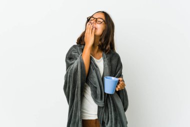 Beyaz arka planda battaniyeli genç Latin kadın gülüyor, kaygısız, doğal duygu..