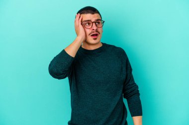 Mavi arka planda izole genç beyaz adam şok oldu, o önemli bir toplantı hatırladı.