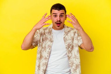Sarı arka planda izole edilmiş genç beyaz adam on numarayı elleriyle gösteriyor..