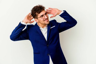 Beyaz arka planda kendini güvende hisseden, elleri başının arkasında olan beyaz bir iş adamı..