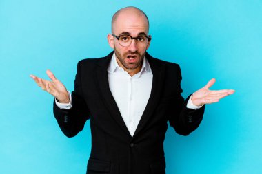Genç, beyaz, kel bir adam mavi arka planda izole edilmiş farklı fotokopi alanlarını gösteriyor, birini seçiyor, parmaklarıyla gösteriyor..