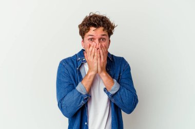 Beyaz arka planda izole edilmiş genç beyaz adam şok olmuş, ağzı ellerle kaplanmış, yeni bir şey keşfetmeye hevesli..