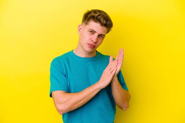 Sarı arka planda izole edilmiş genç beyaz adam enerjik ve rahat hissediyor, ellerini ovuşturuyor kendinden emin..