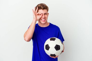 Futbol oynayan genç beyaz adam arka planda izole edilmiş halde heyecanlı. Göze göz hareketi yapıyor..