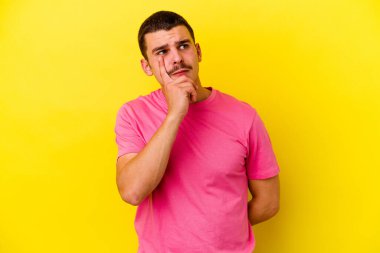 Kafkas asıllı genç adam sarı arka planda izole edilmiş, bir strateji planlıyor, bir işin nasıl olacağını düşünüyor..