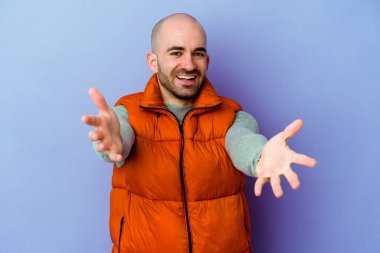 Mor arka planda izole genç beyaz kel adam kameraya sarıldığı için kendinden emin hissediyor..