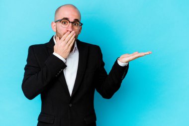 Mavi arka planda izole edilmiş Kafkasyalı genç bir adam, avuç içi fotokopi alanını elinde tutmaktan etkilenmiş..