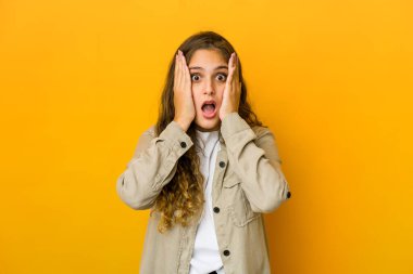 Beyaz bir kadın yüzünün yarısını avuç içiyle kaplayarak eğleniyor..