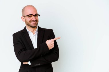 Beyaz arka planda soyutlanmış beyaz saçlı genç bir beyaz adam işaret parmağıyla işaret ederek gülümsüyor..