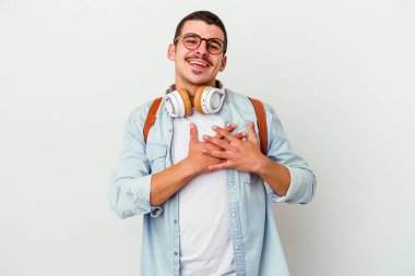 Beyaz arka planda izole edilmiş müzik dinleyen beyaz tenli genç bir öğrenci, avuçlarını göğsüne bastıran dostane bir ifadeye sahiptir. Aşk konsepti.