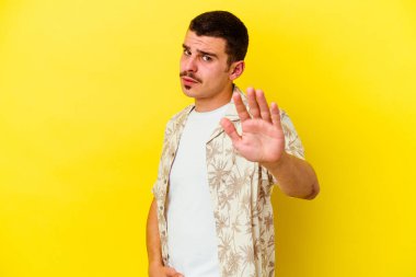 Sarı arka planda izole genç beyaz adam yakın bir tehlike nedeniyle şok oluyor.