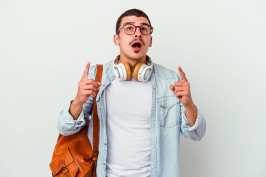 Beyaz arka planda izole edilmiş müzik dinleyen beyaz tenli genç bir öğrenci ağzı açık bir şekilde üst tarafı işaret ediyor..