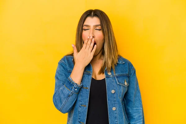 Young indian woman isolated on yellow background yawning showing a tired gesture covering mouth with hand.