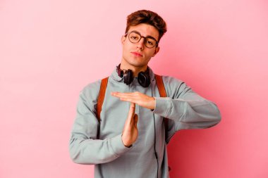 Pembe arka planda izole edilmiş genç bir öğrenci bir mola hareketi gösteriyor..