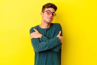 Sarı arka plan kucaklamalarında izole edilmiş genç beyaz adam, kaygısız ve mutlu gülümsüyor..