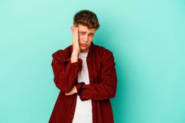 Mavi arka planda izole edilmiş genç beyaz adamın yanakları şişer, yorgun bir ifadesi vardır. Yüz ifadesi kavramı.