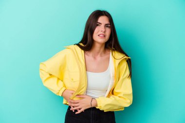 Mavi arka planda karaciğer ağrısı çeken, karnı ağrıyan beyaz bir kadın..