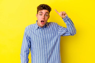 Sarı arka planda izole edilmiş genç beyaz bir adam harika bir fikri, yaratıcılık kavramı var..