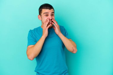 Kafkasyalı genç adam mavi arka planda izole edilmiş korkmuş ve korkmuş..