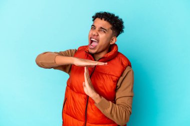 Genç Afro-Amerikalı kıvırcık adam mavi üzerine izole edilmiş bir şekilde mola veriyor..