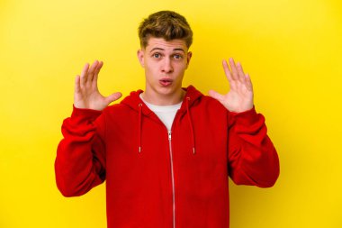 Sarı arka planda izole edilmiş genç beyaz bir adam zaferi ya da başarıyı kutluyor, şaşırıyor ve şok oluyor..