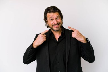 Orta yaşlı Hollandalı adam beyaz arka planda izole edilmiş gülümsüyor, parmaklarını ağıza doğrultuyor..