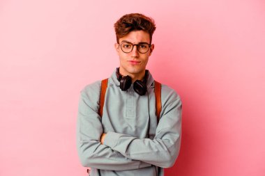 Genç öğrenci pembe arka planda izole edilmiş mutsuz bir şekilde iğneleyici bir ifadeyle kameraya bakıyor..
