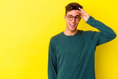 Sarı arka planda izole edilmiş genç beyaz adam yüksek sesle bağırıyor, gözleri açık ve elleri gergin tutuyor..