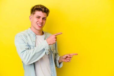 Sarı arka planda izole edilmiş genç beyaz adam işaret fişekleriyle işaret ederek heyecanlanıyor..