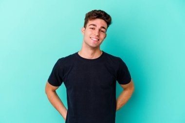 Mavi arka planda izole edilmiş genç beyaz adam mutlu, güler yüzlü ve neşeli.