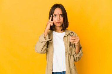 Genç İspanyol kadın elinde eski bir anahtarla parmağıyla tapınağı işaret ediyor, düşünüyor ve bir göreve odaklanıyor..