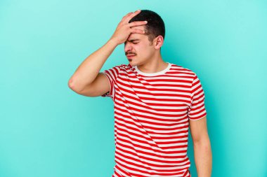 Genç beyaz adam mavi arka planda izole edilmiş tapınaklara dokunuyor ve başı ağrıyor..