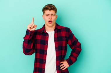 Kafkasyalı genç bir adam mavi arka planda izole edilmiş. Bir fikri, ilham verici bir fikri var..