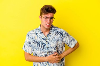 Sarı arka planda karaciğer ağrısı çeken, karnı ağrıyan genç beyaz bir adam..