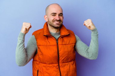 Kafkasyalı kel adam mor arka planda izole edilmiş tasasız ve heyecanlı bir şekilde tezahürat yapıyor. Zafer konsepti.