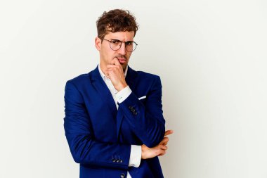 Beyaz arka planda izole edilmiş genç bir beyaz iş adamı şüpheli, belirsiz, seni muayene ediyor..