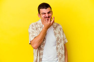 Kafkasyalı genç adam sarı arka planda izole edilmiş iki seçenek arasında kuşkulanıyor.