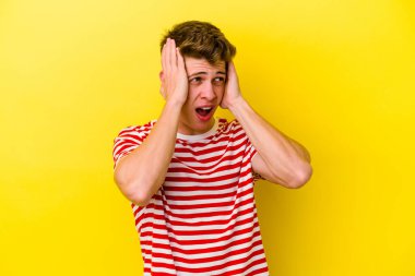 Kafkasyalı genç adam sarı arka planda izole edilmiş kulakları kulaklarıyla kapatıyor çok fazla ses duymamaya çalışıyor..
